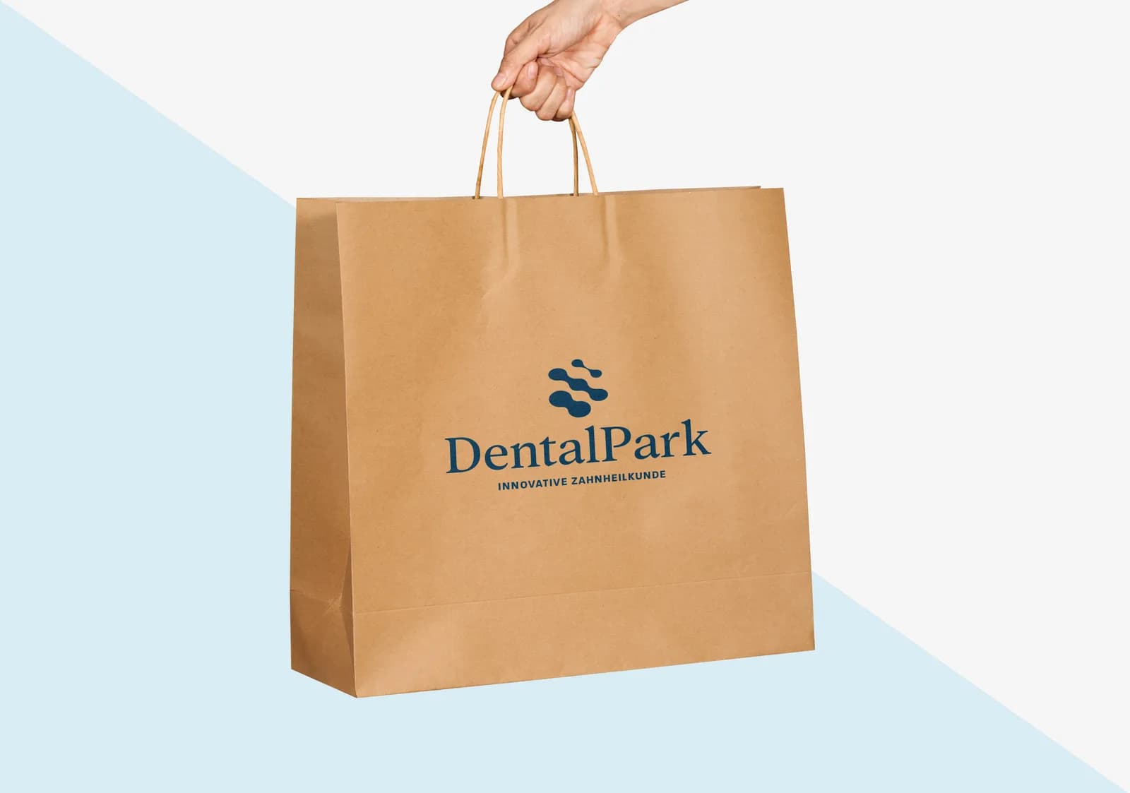 Papiertragetasche aus Kraftpapier mit dunkelblauem Logoaufdruck, von einer Hand gehalten